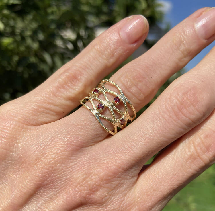 טבעת נופך מדהימה זו מציגה אלגנטיות פשוטה בעיצוב שלה. הטבעת כוללת אבן חן אדומה טבעית בחיתוך עגול ובגימור רצועה מרוקעת.