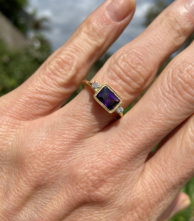 This gorgeous and elegant women's ring features an octagon-cut natural amethyst gemstone with two round-cut dazzling clear quartz. This beautiful ring is enhanced with a high polish finish.
