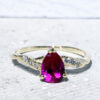 This gorgeous ruby ring displays simple elegance in its design. The ring features a stunning pear ruby which is claw set and nestled by six glistening round cut clear quartz.