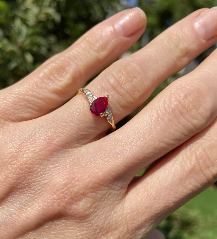 This gorgeous ruby ring displays simple elegance in its design. The ring features a stunning pear ruby which is claw set and nestled by six glistening round cut clear quartz.