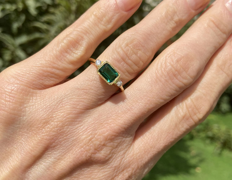 This gorgeous and elegant women's ring features an octagon-cut natural emerald gemstone with two round-cut dazzling clear quartz. This beautiful ring is enhanced with a high polish finish.
