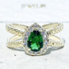 The spectacular design of this emerald ring is a contemporary take on a classic choice which will be much loved by anyone who loves bright and bold jewelry. The pear cut emerald is flanked on every side by high quality clear quartz gemstones.