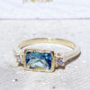 Это великолепное и элегантное женское кольцо украшено синим топазом восьмиугольной огранки и двумя ослепительно прозрачными кварцами круглой огранки. Это красивое кольцо отполировано до блеска.