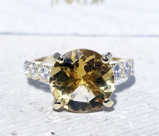 An absolute stunner, classic natural citrine engagement ring with a round cut gemstone of your choice as it’s centre stone and with round cut clear quartz on the band to further accentuate it.