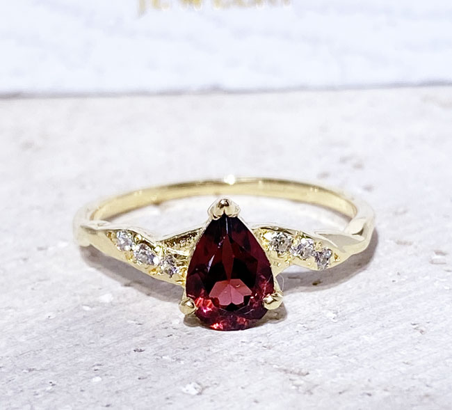 An absolute stunner, classic natural red garnet engagement ring with a pear cut gemstone of your choice as it’s centre stone and with round cut clear quartz on the band to further accentuate it.
