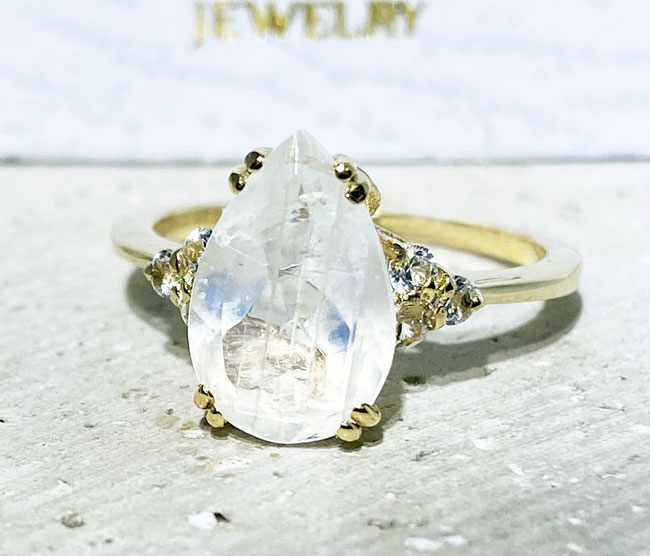 An absolute stunner, classic natural moonstone engagement ring with a pear cut gemstone of your choice as it’s centre stone and with round cut clear quartz on the band to further accentuate it.
