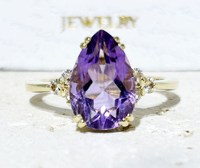 An absolute stunner, classic natural purple amethyst engagement ring with a pear cut gemstone of your choice as it’s centre stone and with round cut clear quartz on the band to further accentuate it.