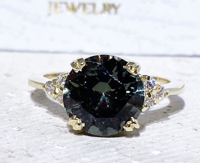 An absolute stunner, classic green tourmaline engagement ring with a round cut gemstone of your choice as it’s centre stone and with round cut clear quartz on the band to further accentuate it.