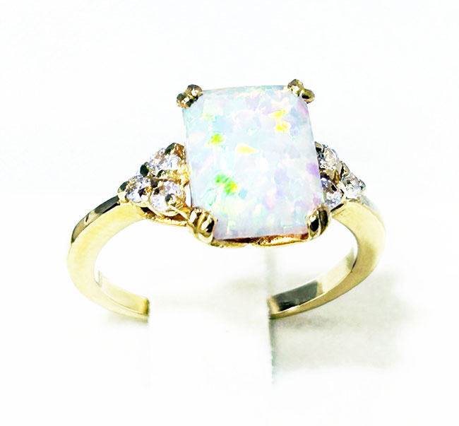 An absolute stunner, classic white opal engagement ring with an emerald cut gemstone of your choice as it’s centre stone and with round cut clear quartz on the band to further accentuate it.