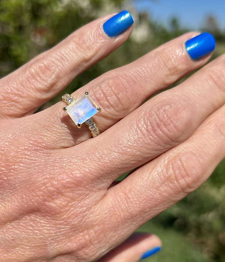 An absolute stunner, classic natural moonstone engagement ring with an emerald cut gemstone of your choice as it’s centre stone and with round cut clear quartz on the band to further accentuate it.